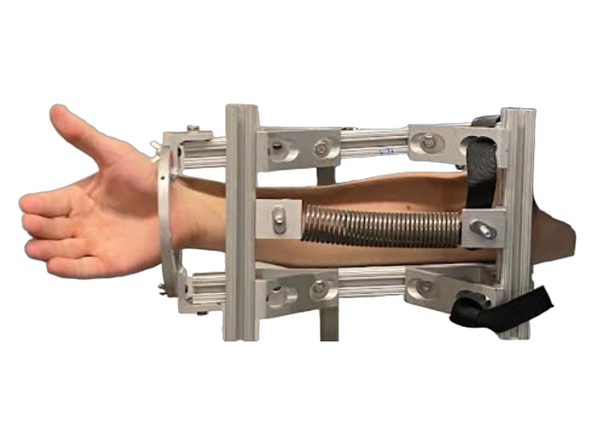 First rough prototype: an aluminum-extrusion frame around the forearm with a coil spring running between a wrist ring and an elbow brace